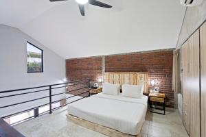 1 dormitorio con cama y pared de ladrillo en Ambara U6 Loft by Hombali en Canggu