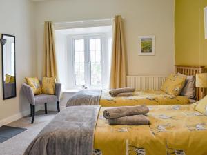 two beds in a bedroom with yellow sheets at Rooftops - Uk34065 in Grassington