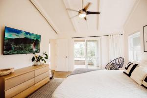 プリンスビルにあるBOHO New Construction: On Golf Course/views/Hot tub AC walk to market and beachのベッドと壁にテレビが掛かった寝室