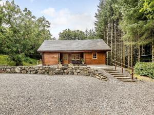 a log cabin in the woods with a stone wall at Larch in Killin
