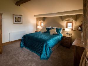 Schlafzimmer mit einem Bett mit blauer Decke in der Unterkunft Cedar Barn - Uk33352 in Buttershaw