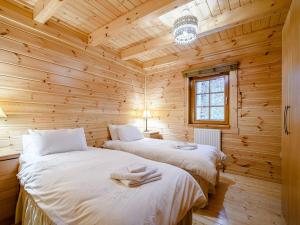 2 camas en una cabaña de madera con ventana en Larch en Killin