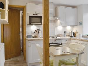 uma cozinha com armários brancos e uma mesa em Little Nook em Ambleside
