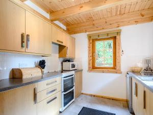a kitchen with wooden cabinets and a window at Larch - Uk31134 in Killin