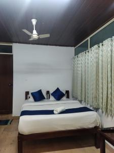 a bedroom with a bed with blue pillows and a ceiling at Lovely Home Stay Munnar in Munnar