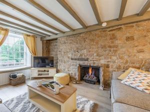 a living room with a fireplace and a stone wall at Catmint Cottage in Highpeak Junction