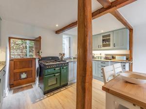 a kitchen with a green stove and a table at Catmint Cottage in Highpeak Junction