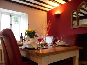 Tintern Abbey Cottage في تينتيرن: طاولة غرفة الطعام مع كؤوس النبيذ والزهور عليها