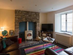 a living room with a stone fireplace and a couch at Tintern Abbey Cottage in Tintern