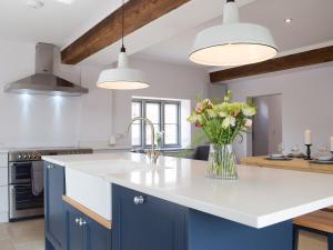 una cocina con armarios azules y un jarrón de flores en The Dairy - Uk34564, en Whitchurch