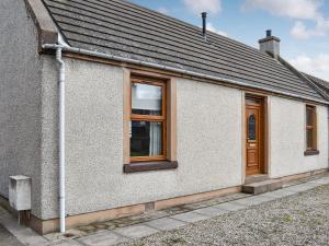 a white building with windows and a roof at Sea Breeze Cottage in Buckie