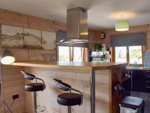 a kitchen with a counter and stools at a bar at Seal Rocks in Lendalfoot