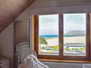 a bedroom with a window with a view of the beach at Seal Rocks in Lendalfoot