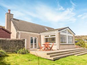 a patio with a table and chairs in front of a house at Taigh Na Beadan in Valtos