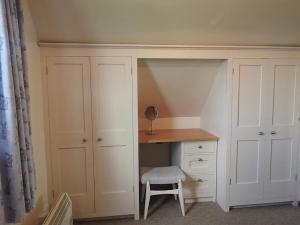 um armário com uma secretária e uma cadeira num quarto em Marshfield Annex em Wingfield