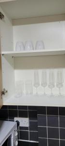 una fila di bicchieri da vino su una mensola in cucina di 16 Decent Homes a Dukinfield
