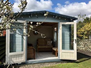 a small shed with a porch and a chair at Maggies Den in Gatehouse of Fleet