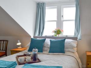 a bedroom with a bed with blue pillows and a window at Rock Cottage in Ardentinny