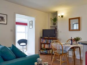 ein Wohnzimmer mit einem blauen Sofa und einem Tisch in der Unterkunft Rock Cottage in Ardentinny
