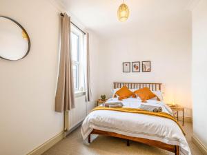 ein Schlafzimmer mit einem Bett mit orangefarbenen Kissen und einem Fenster in der Unterkunft Wisteria Cottage in Heacham
