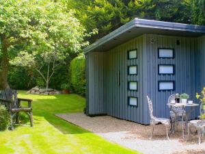 un cobertizo verde con una mesa y sillas en un patio en Apple Tree Cottage, en Bassenthwaite