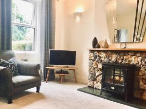 a living room with a fireplace and a television at Apple Tree Cottage in Bassenthwaite