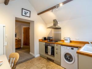 a kitchen with a washing machine and a sink at Wren Cottage in Sutton