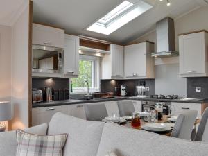 a kitchen with white cabinets and a table with chairs at Pheasant - Uk31514 in Calthwaite