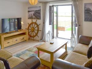 a living room with a couch and a tv and a table at Riverbank Cottage in Reedham