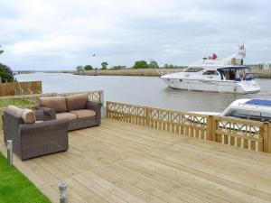 a wooden deck with a boat in the water at Riverbank Cottage in Reedham