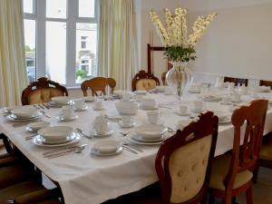 a dining room table with white dishes and a vase of flowers at Littlewood in Saint Columb Major