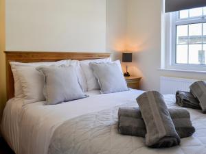 Un dormitorio con una cama blanca con almohadas y una ventana en Llwynon Cottage, en Llandudno