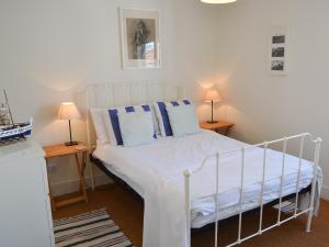 a bedroom with a white bed with blue pillows at Jicklings in Wells next the Sea
