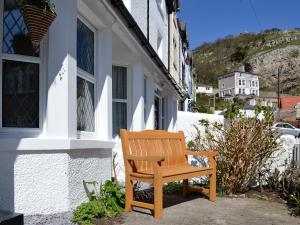 un banco de madera sentado fuera de un edificio en Llwynon Cottage, en Llandudno