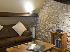 sala de estar con sofá y pared de piedra en Old Barn Cottage en Lockton
