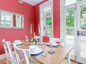 a dining room with a wooden table and white chairs at Station House in Millers Dale