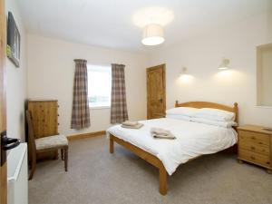 a bedroom with a bed and a chair and a window at The Paddock in Portmahomack