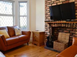 sala de estar con sofá y chimenea en Llwynon Cottage, en Llandudno