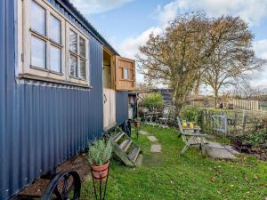 ein blaues Haus mit einer Bank und einem Tisch in der Unterkunft Elsies Hut in Albourne
