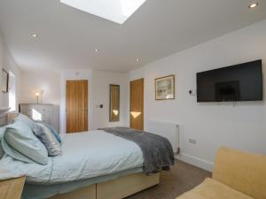 um quarto com uma cama e uma televisão de ecrã plano em Penthwaite em Leyburn