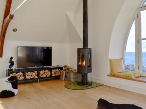 a living room with a fireplace and a flat screen tv at Rathven Parish Church Hall in Portessie