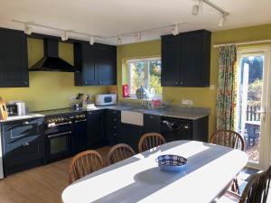 a kitchen with black cabinets and a table with chairs at Orchard House in Baconsthorpe