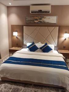 a bedroom with a large bed with blue pillows at ركن تالا للشقق المخدومة in Buraydah