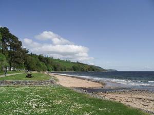 Glenurguhart的住宿－Thistle Lodge - Uk7051，海滩上有人坐在水边的长凳上