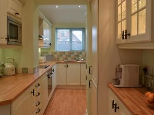 a kitchen with white cabinets and a window at Seaholme in Seahouses