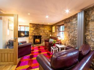 a living room with leather furniture and a stone wall at Foxes Reach in Trelleck