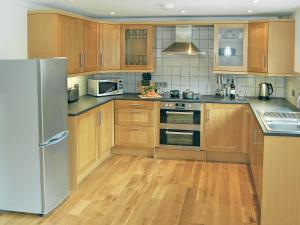 a kitchen with wooden cabinets and a stainless steel refrigerator at Home Park Farm Cottages B in Lanteglos