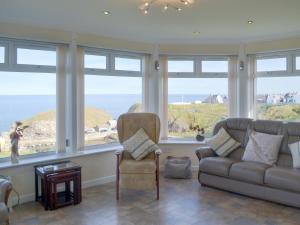 uma sala de estar com um sofá, uma cadeira e janelas em Seabreezes - Uk30690 em Portknockie