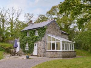 a stone cottage with ivy on the side of it at Quarrymans Cottage in Linkinhorne