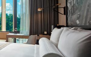 a hotel room with a bed and a desk and windows at Hotel Stripes Kuala Lumpur, Autograph Collection in Kuala Lumpur